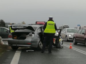 droga, rozbity srebrny samochód, obok policjant