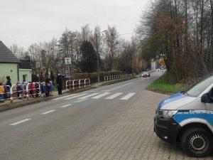 Policjant z przedszkolakami przed przejściem dla pieszych