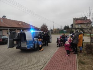 Policjant z przedszkolakami przed radiowozem