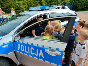 policjant siedzi w radiowozie, obok dzieci