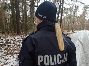 policjantka stoi na drodze w lesie
