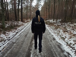 policjantka stoi na drodze w lesie