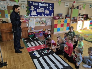 sala w przedszkolu, policjantka pokazuje dzieciom mate edukacyjną