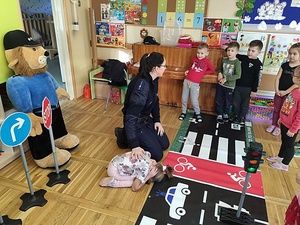 sala w przedszkolu, policjantka pokazuje dzieciom postawę żółwia