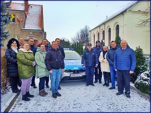 Komendant Powiatowy Policji młodszy inspektor Dariusz Smoliński wraz z Wójtem Gminy Udanin Wojciechem Płaziukiem, funkcjonariuszami Posterunku Policji w Udaninie oraz lokalnymi samorządowcami na tle nowego radiowozu marki KIA CEED