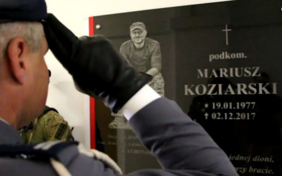 Policjant salutuje przed tablicą pamiątkową