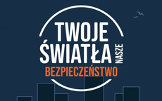 Biało-pomarańczowy napis Twoje światła nasze bezpieczeństwo na granatowym tle