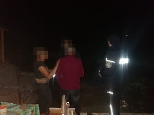 wieczór, trzy osoby rozmawiają, obok policjant