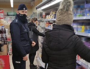 policjant wraz z dwiema kobietami stoi przed witryną