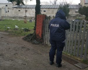 Zdjęcie przedstawia policjantkę, która stoi przy ogrodzeniu i telefonuje