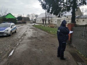 zdjęcie przedstawia radiowóz a obok policjantkę, która trzyma telefon komórkowy