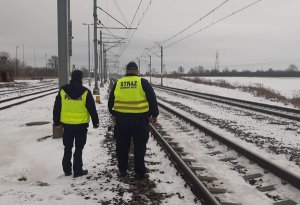 zdjęcie przedstawia policjanta i funkcjonariusz Straży Ochrony Kolei przy torach kolejowych