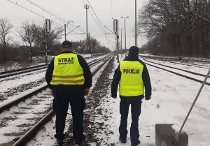 zdjęcie przedstawia policjanta i funkcjonariusz Straży Ochrony Kolei przy torach kolejowych