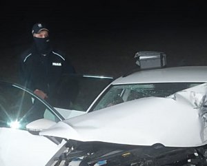 Zdjęcie przedstawia rozbity samochód, za nim stoi policjant