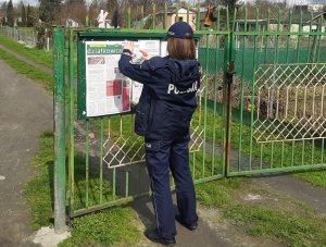 policjantka umieszczenia ulotkę na tablicy ogłoszeniowej na terenie ogródków działkowych