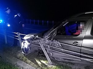 zdjęcie przedstawia rozbity samochód, przed nim stoi policjant