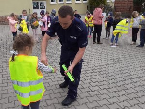 policjant daje dziecku opaskę odblaskową
