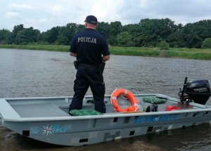 rzeka, policjant stoi w łódce