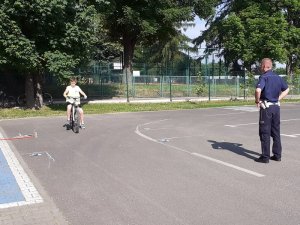 dziecko jedzie na rowerze, obok stoi policjant