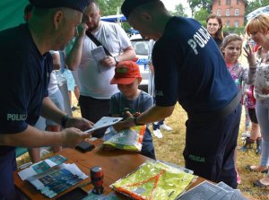 dwóch policjantów stoi przy stoliku, na którym leżą ulotki i elementy odblaskowe