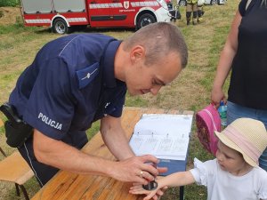 policjant przybija pieczątkę dziecku