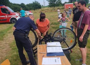 policjant znakuje rower podczas festynu